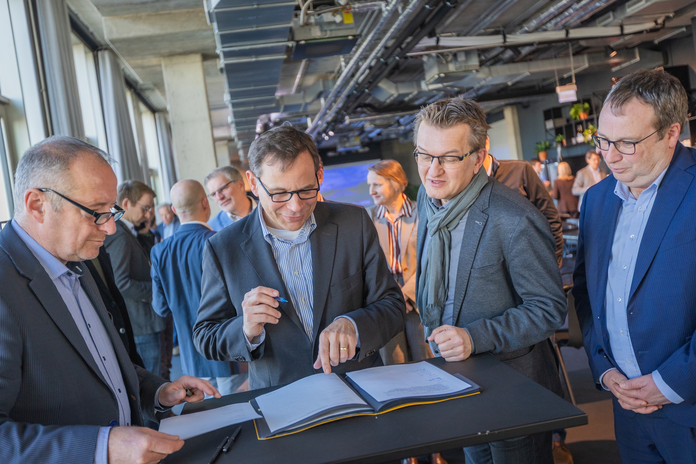 Das Bild zeigt vier Männer bei einer Vertragsunterzeichnung, außen im Bild NRW-Verkehrsminister Oliver Krischer.