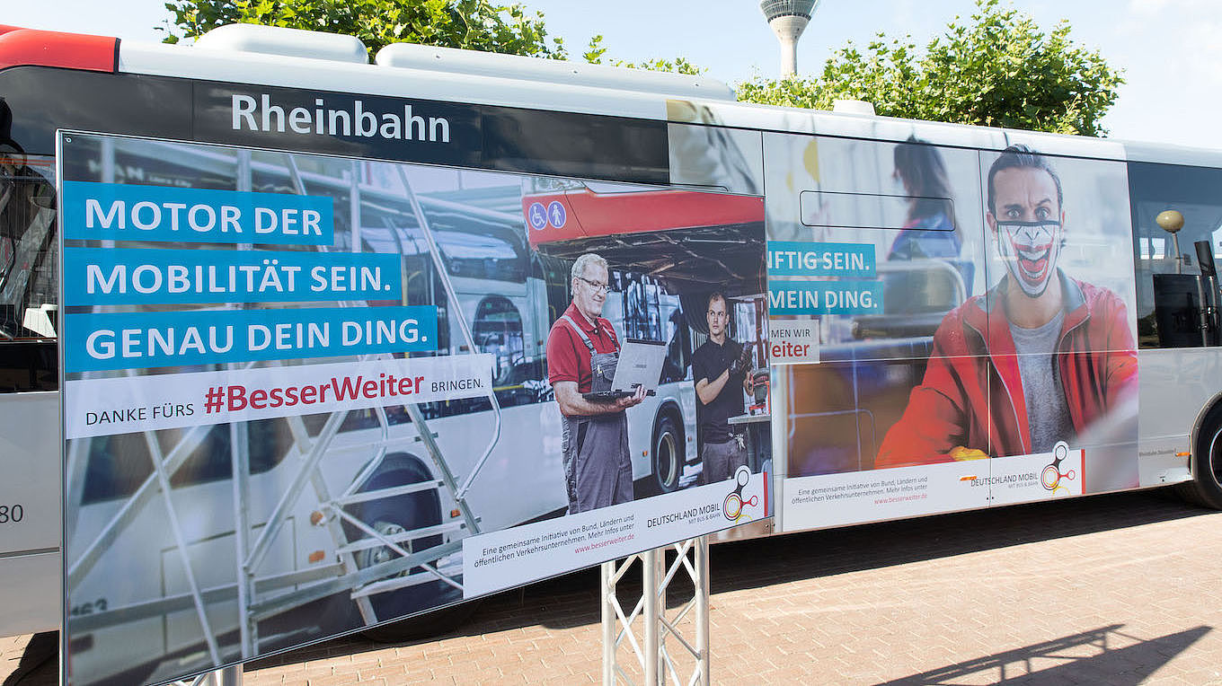 Außenaufnahme eines Busses, auf dem Werbung zur Kampagne "Besser Weiter" aufgeklebt ist.