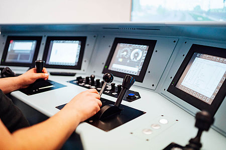 Ein Mann sitzt vor einem Fahrsimulator und steuert einen virtuellen Zug. 