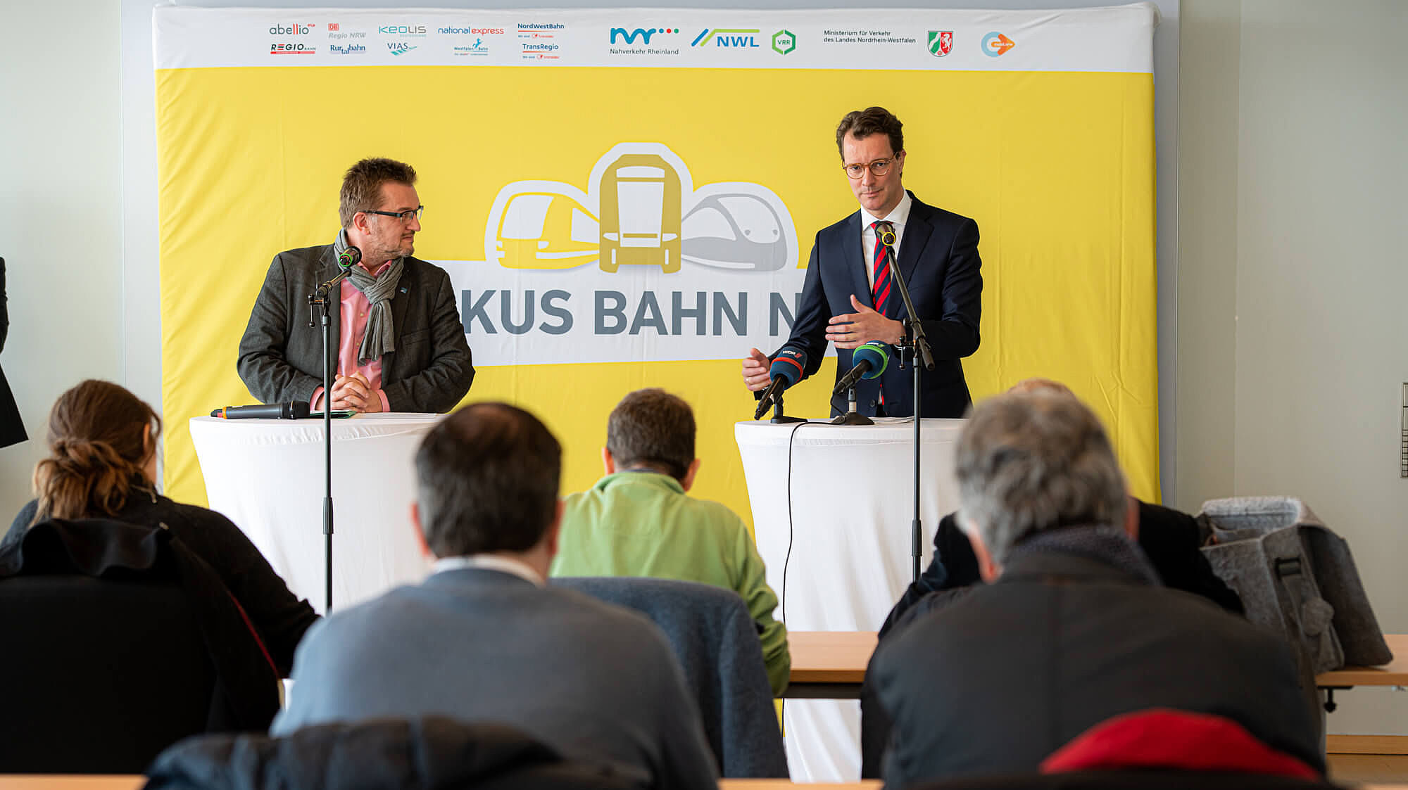 NRW-Verkehrsminister Hendrik Wüst steht an einem Podium und hält eine Rede. Daneben steht Joachim Künzel (Geschäftsführer des NWL) ebenfalls an einem Podium.
