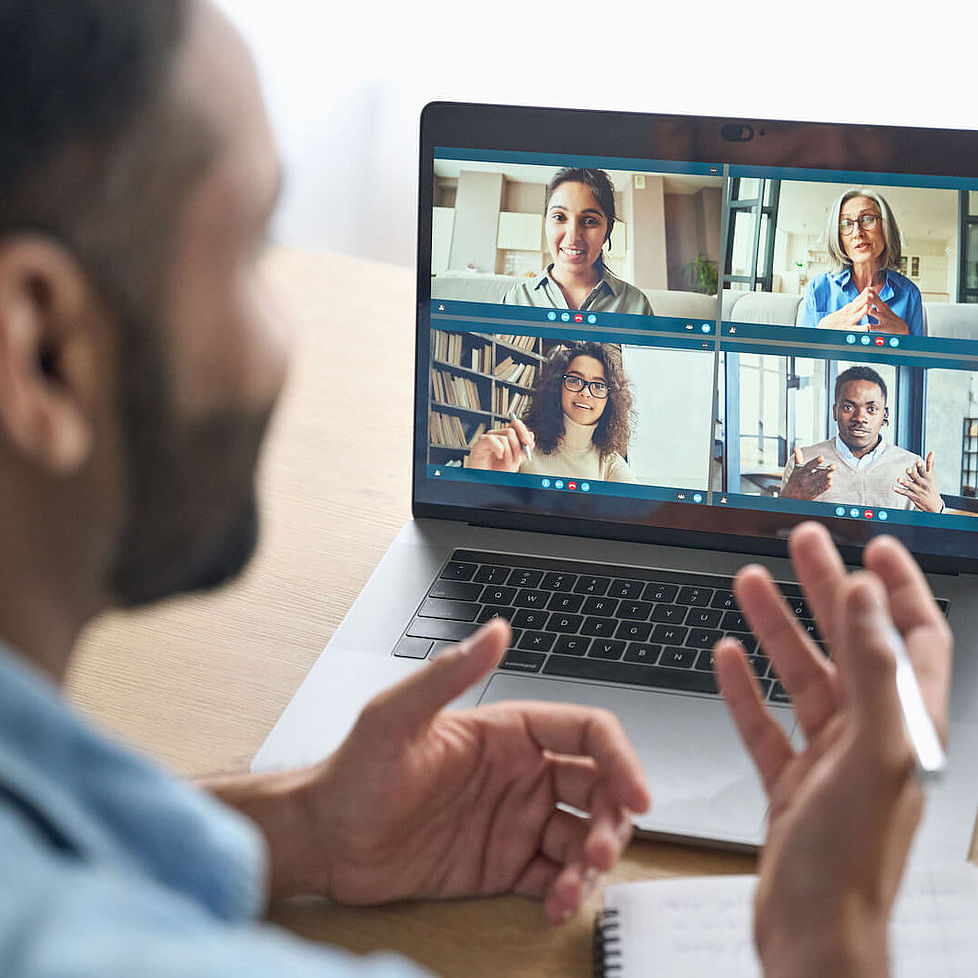 Ein Mann sitzt vor einem Laptop in einen Video-Chat mit 4 anderen Personen.