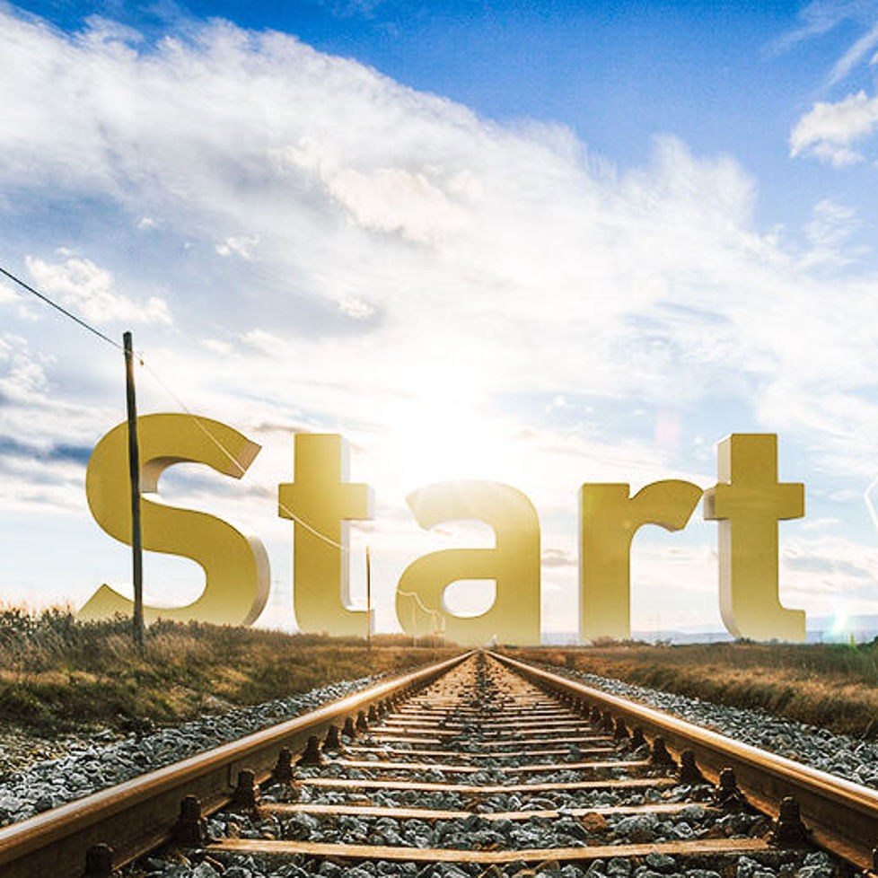 Panoramaansicht einer Landschaft durch die ein Bahngleis verläuft. Am Ende des Gleises stehen Buchstaben die das Wort "Start" bilden.