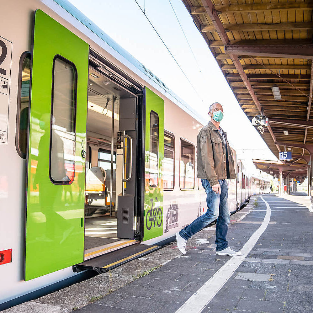 Ein Mann steigt aus einem grünen Zug der S-Bahn Rhein-Ruhr