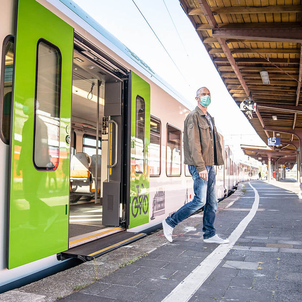 Ein Mann steigt aus einem grünen Zug der S-Bahn Rhein-Ruhr.